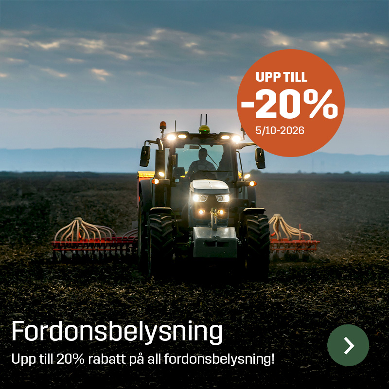Traktor med tänd arbetsbelysning kör på åkermark med ett brett redskap bakom. Sagros fordonsbelysning används för att ge ljus runt lantbruksmaskiner vid arbete i fält.