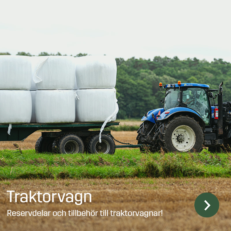 Blå traktor drar en tvåaxlad vagn lastad med vitplastade balar över ett fält. Bilden visar traktorsläp i lantbruksmiljö, en maskintyp som Sagros erbjuder slitdelar, reservdelar och tillbehör till.